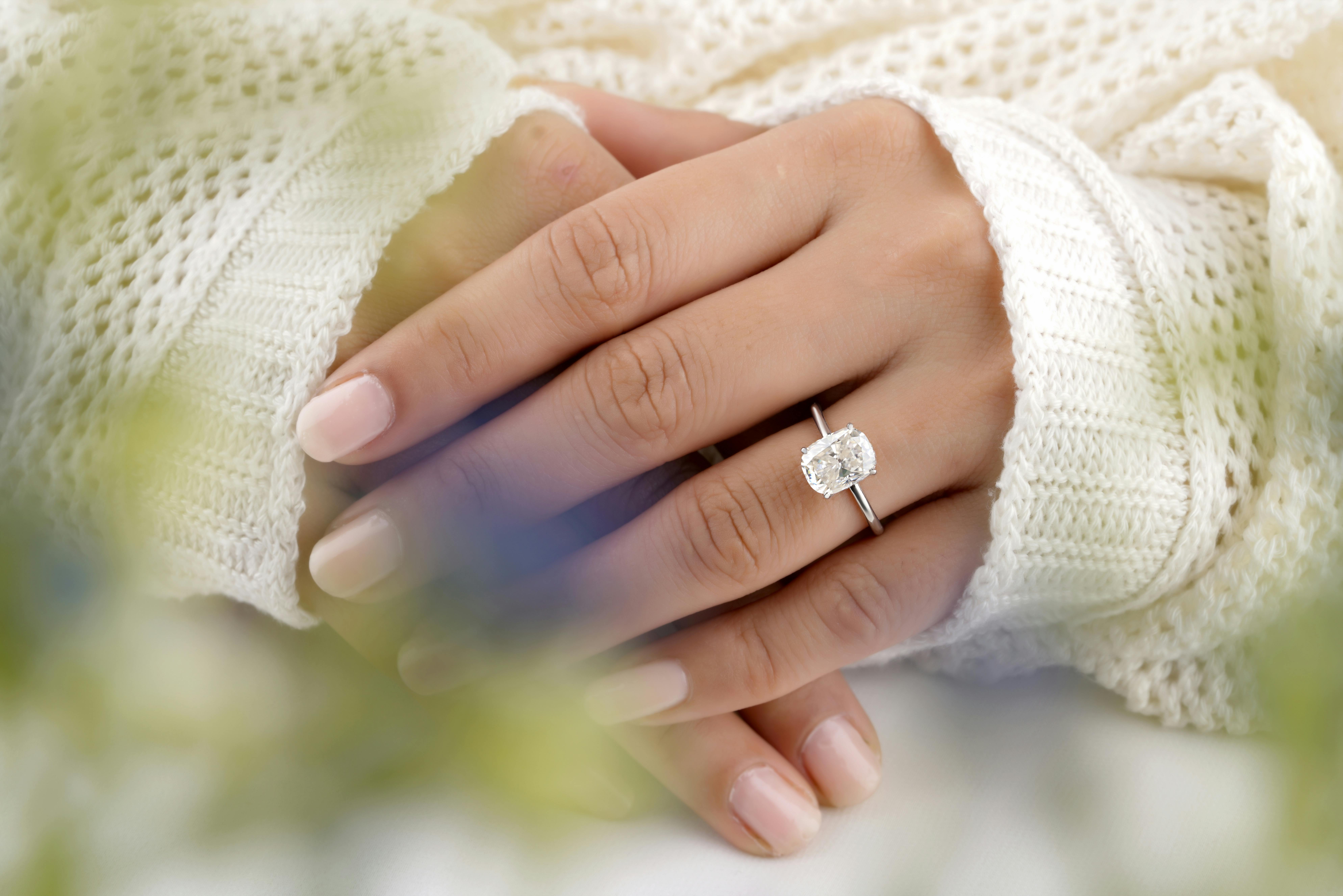 Woman wearing a custom cushion cut diamond solitaire engagement ring